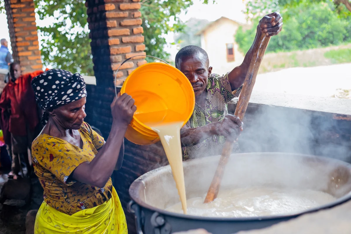 Vorbereitung von nahrhaftem Porridge in Burundi - das Projekt „Ein Becher am Tag“ von Helfende Hände ermöglicht durch lokale Produktion täglich warme Mahlzeiten für tausende Kinder.