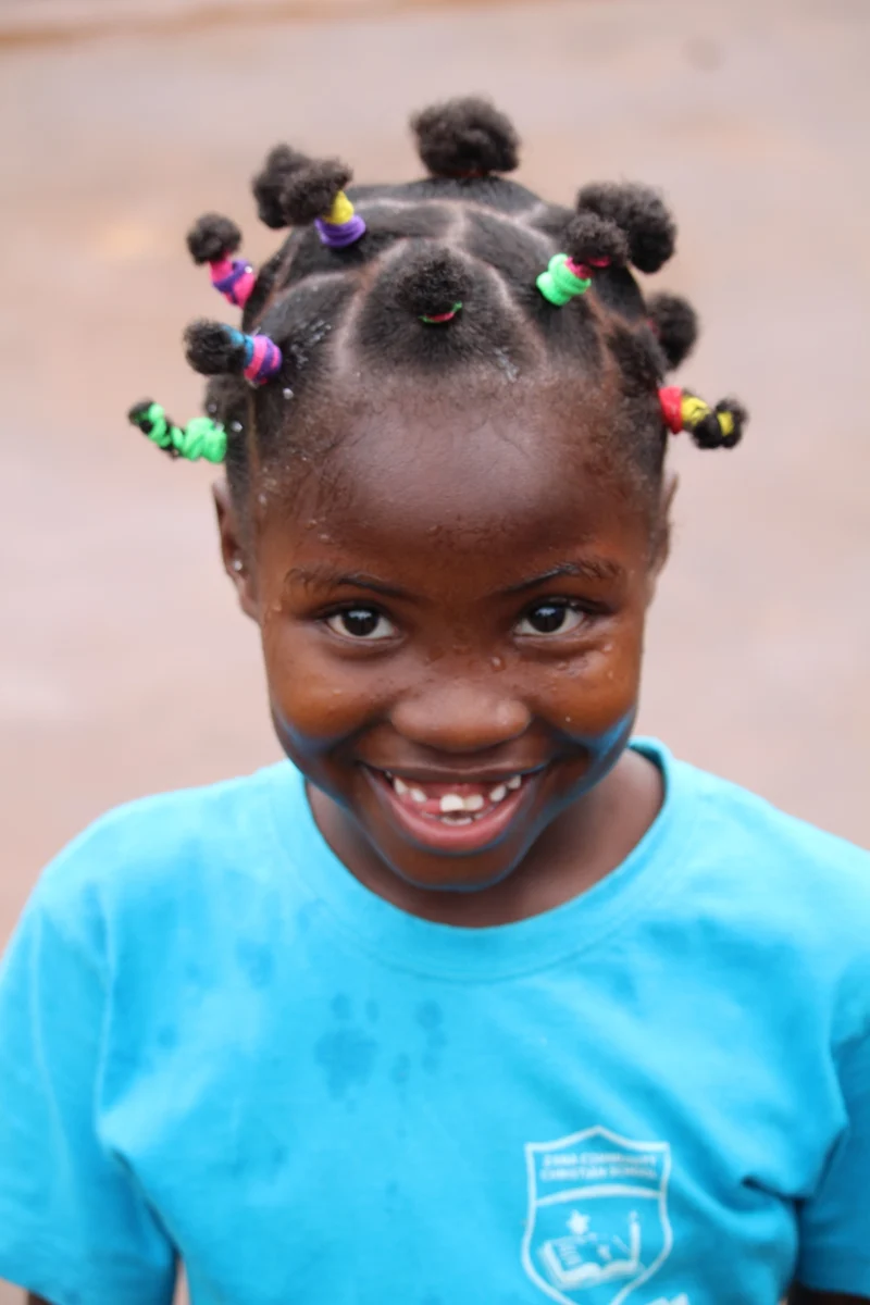 Lachendes Mädchen in Schuluniform der Zana Community Christian School in Uganda – Teil des Schulprojekts für bessere Bildungschancen.