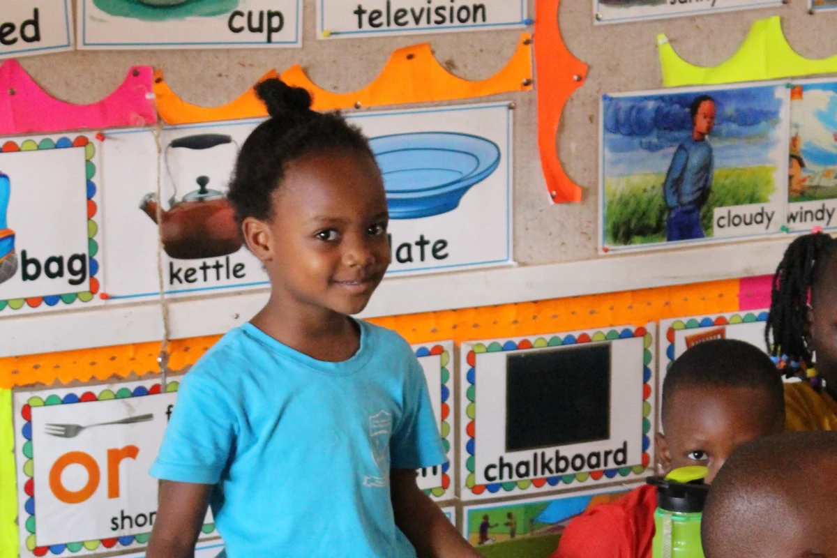 Ein Mädchen in Uganda lächelt im Klassenzimmer des Zana-School-Projekts. Das Bildungsprojekt gibt Kindern Hoffnung und bessere Zukunftsperspektiven.